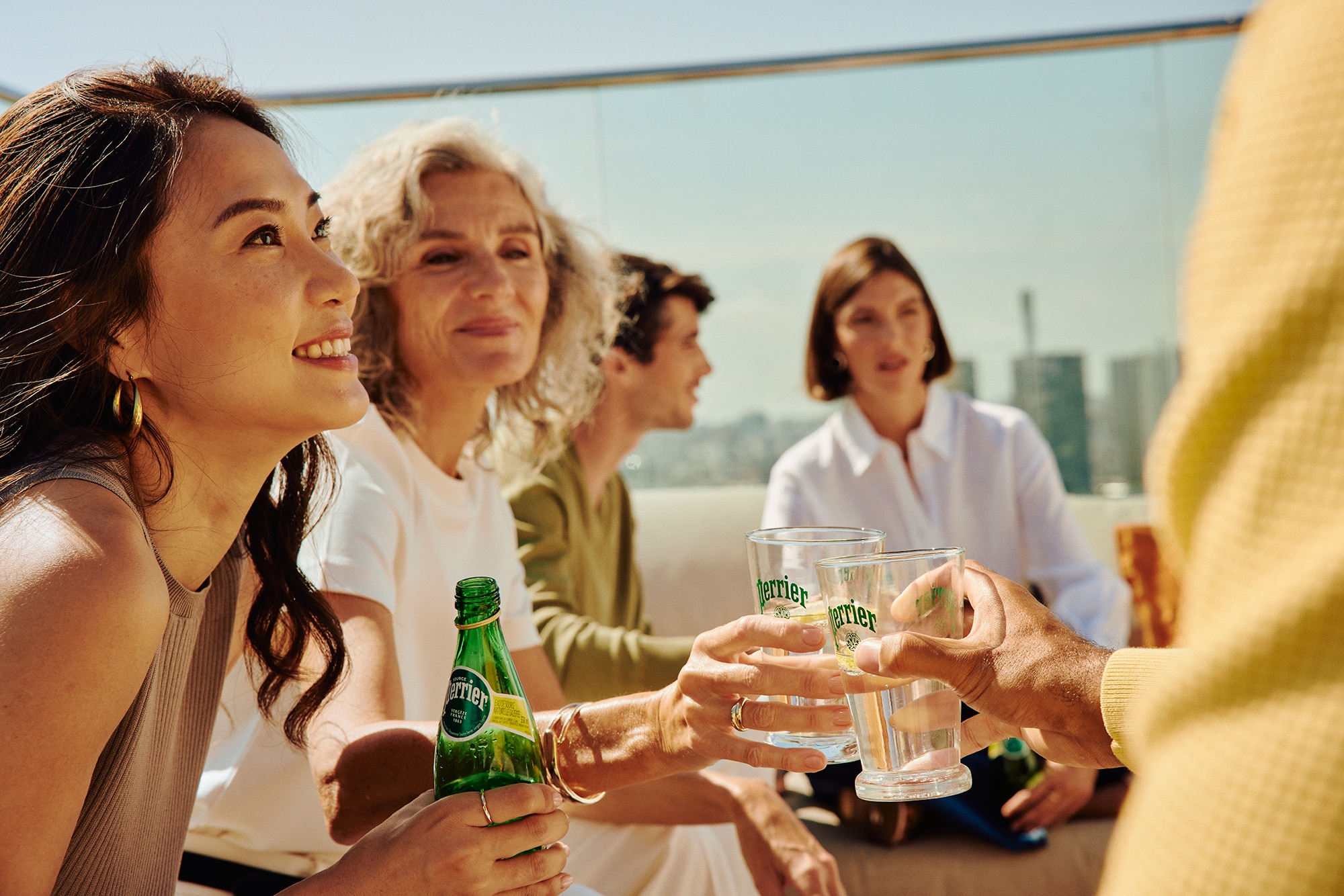 A group of people holding Perrier drinks and a bottle